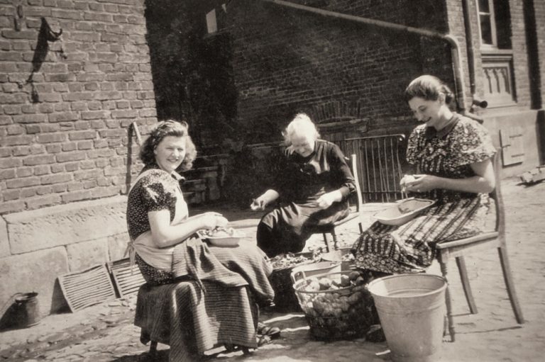 Foto von 1941 drei Bäuerinnen sitzen auf dem Hof und schälen Kartoffeln für das Konfirmationsfest