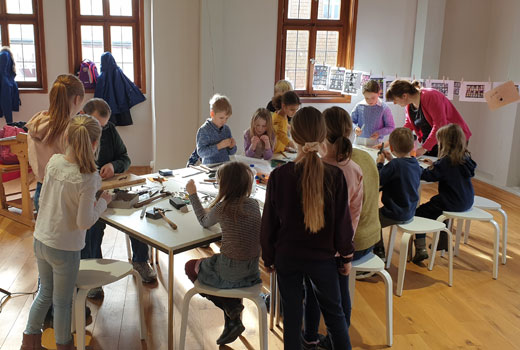 Thema Museums Pädagogik Kinder basteln gemeinsam am großen Tisch im Museum